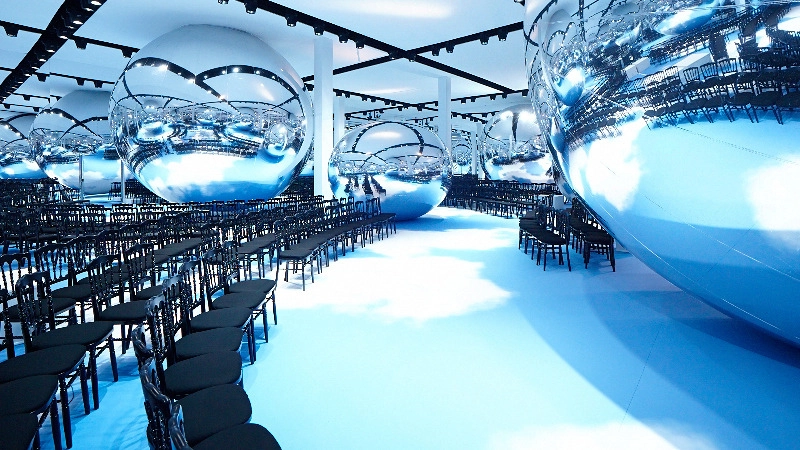 Dior Fall/Winter 2013 fashion show set featuring giant mirrored spheres above the runway seating.